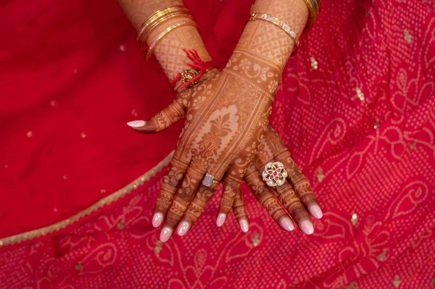 A close view of decorated hands against bright pink fabric