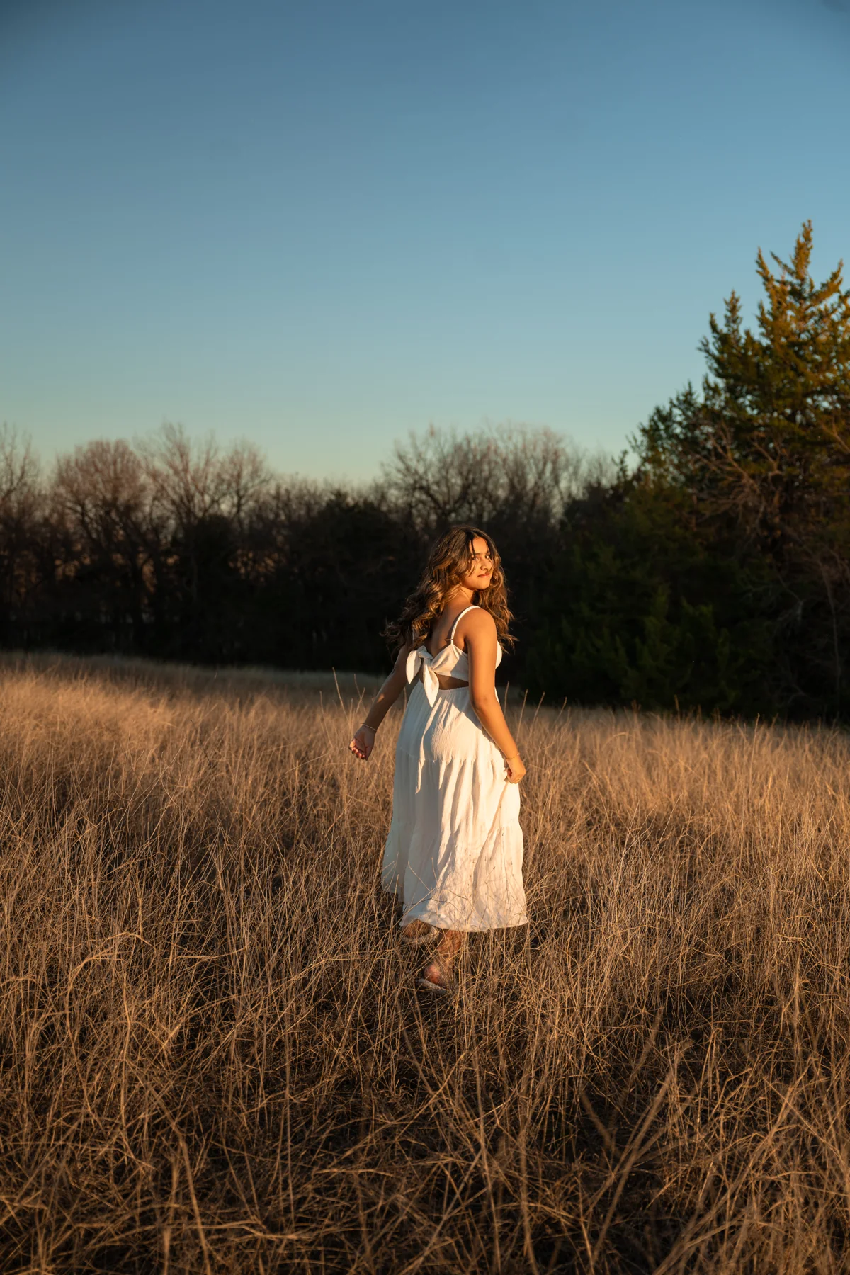 Portrait in a white dress in a golden field beneath a blue sky