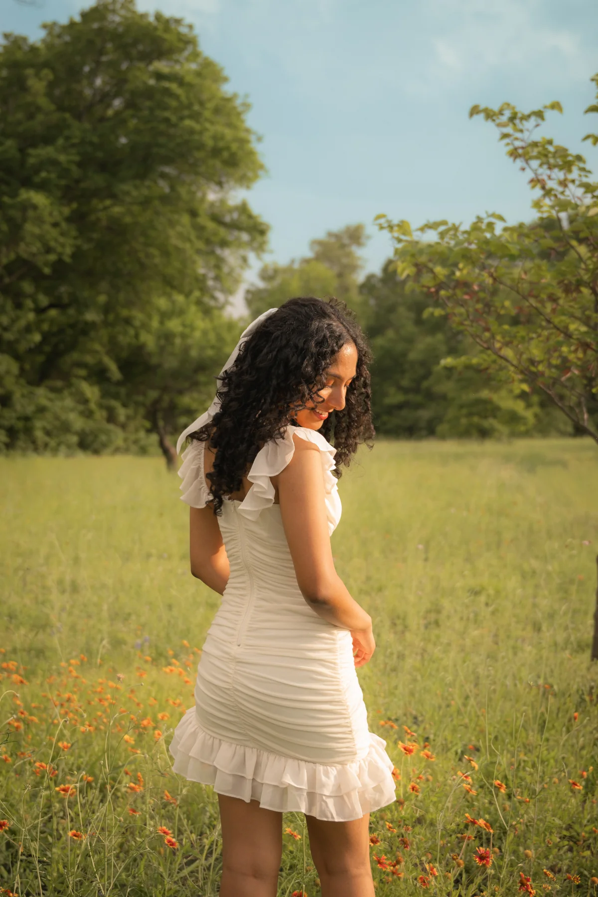 A person in a white dress looking back in a green meadow