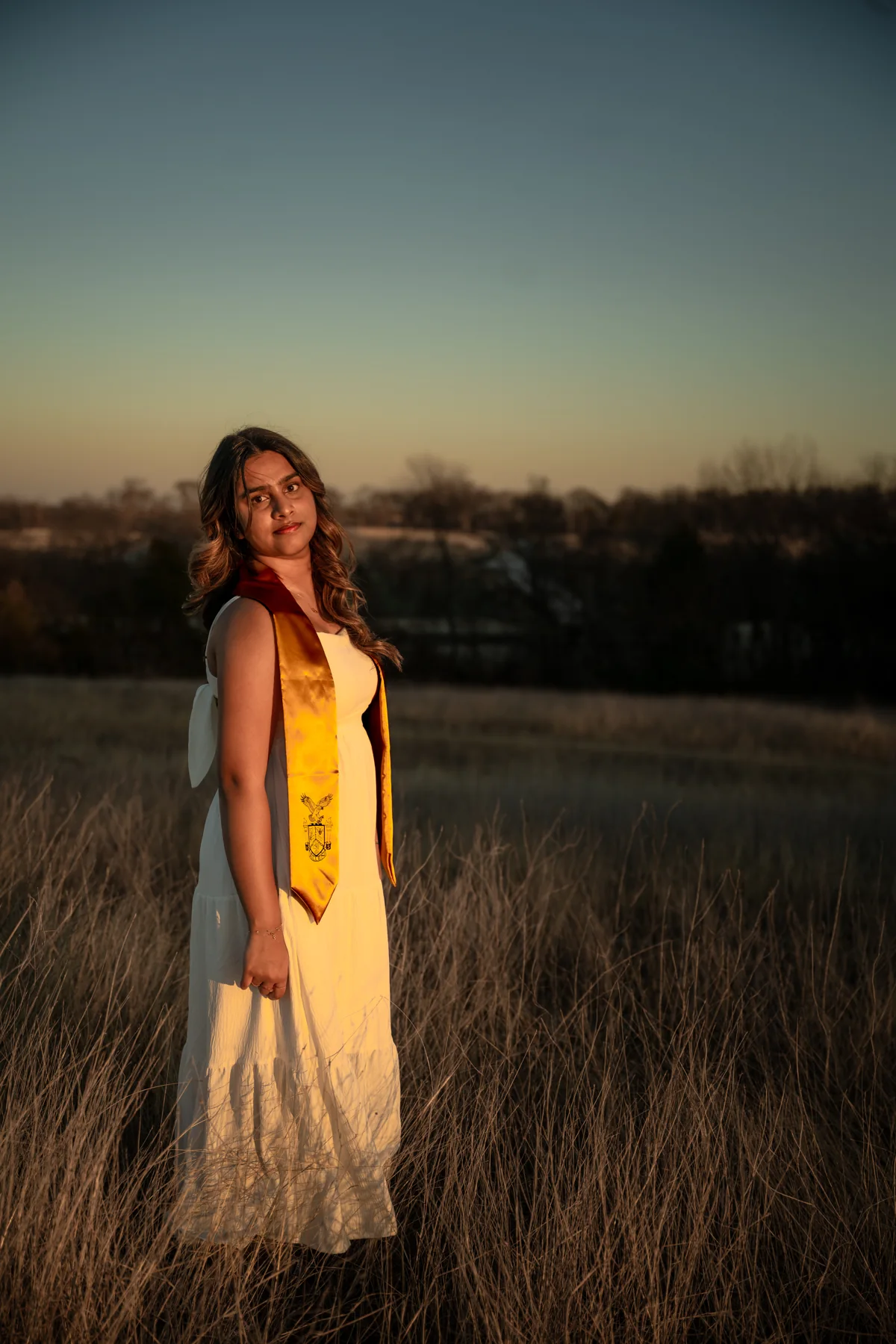 Graduate wearing a yellow stole in warm sunset light