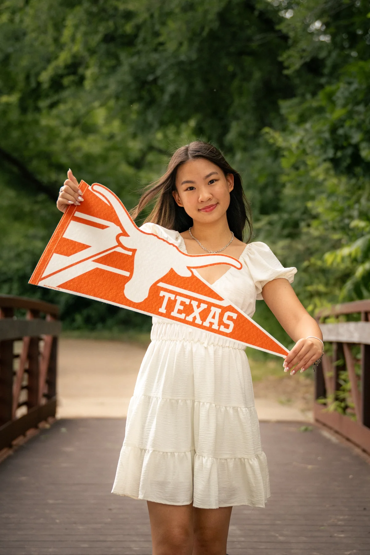 Graduate holding an orange Texas pennant outdoors