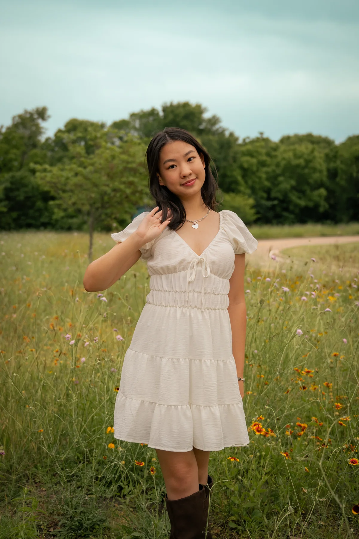 Portrait in a white dress holding a flower on a quiet road