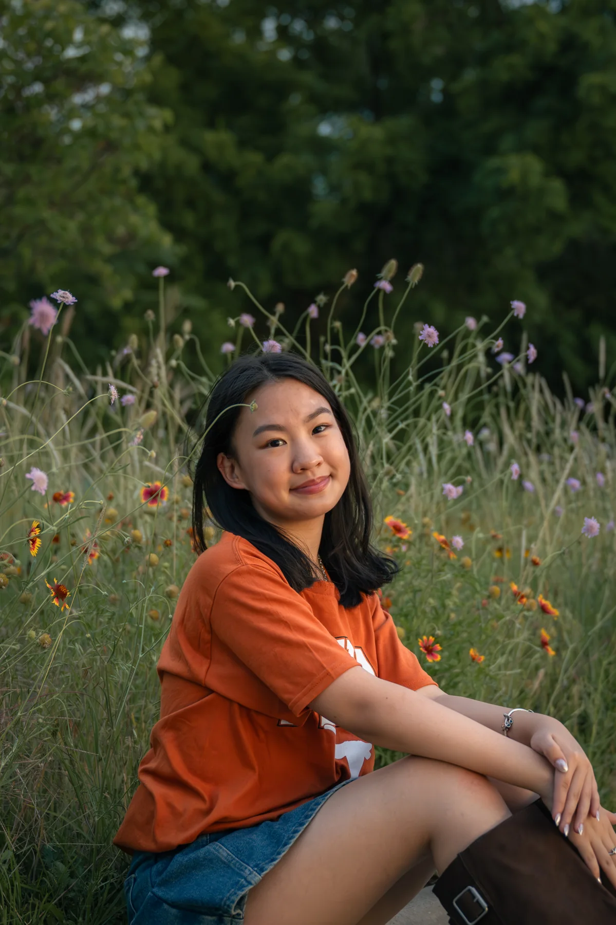 Seated portrait in an orange shirt beside tall grass