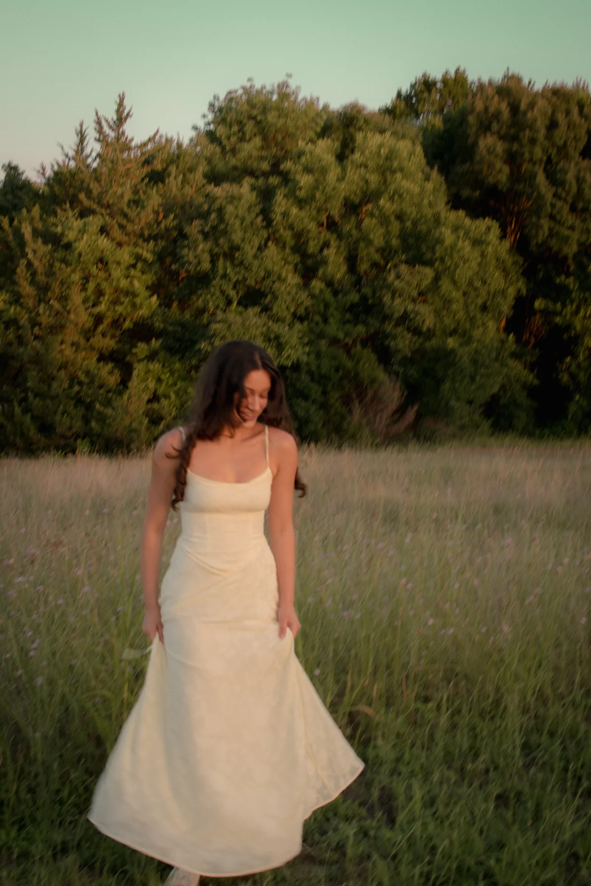 A person in a flowing white dress walking through a meadow