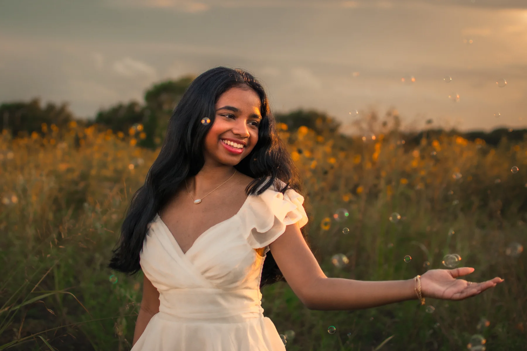 Portrait in a white dress with an open hand against a sunset field