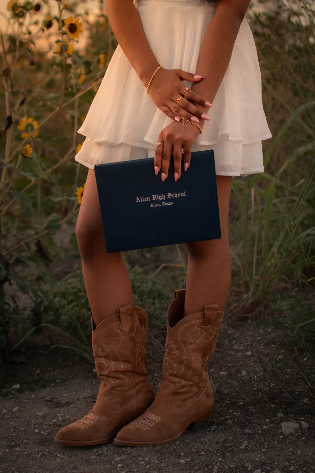 A close view of a navy graduation cap held above cowboy boots